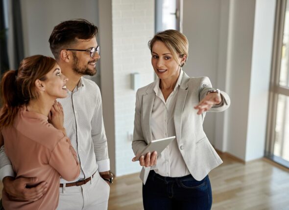 happy-real-estate-agent-talking-couple-while-showing-them-new-apartment_637285-6095