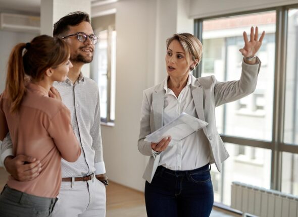 young-couple-communicating-with-real-estate-agent-while-buying-their-new-home-focus-is-agent_637285-6083