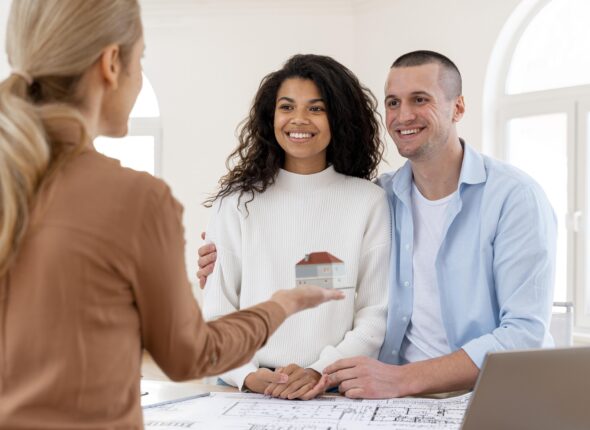 smiley-embraced-couple-conversing-with-female-realtor